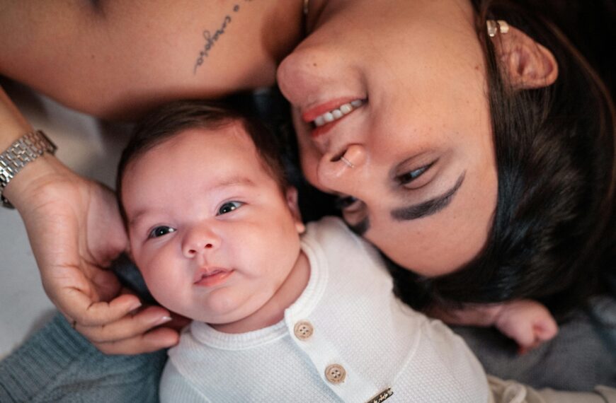 A tender moment between a mother and her baby lying together indoors.