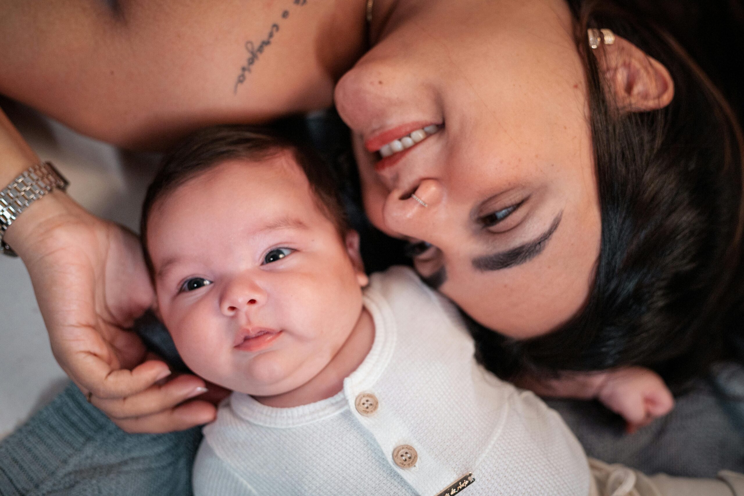 A tender moment between a mother and her baby lying together indoors.